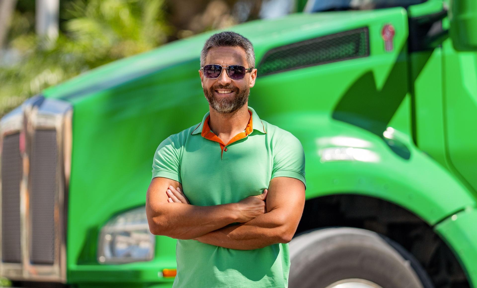 Handsome man driver in front of green truck. Trucking owner. Truck driver. Man trucker driver near lorry truck. Transportation vehicles. Semi trucks vehicle. Hispanic man trucker. Eco service