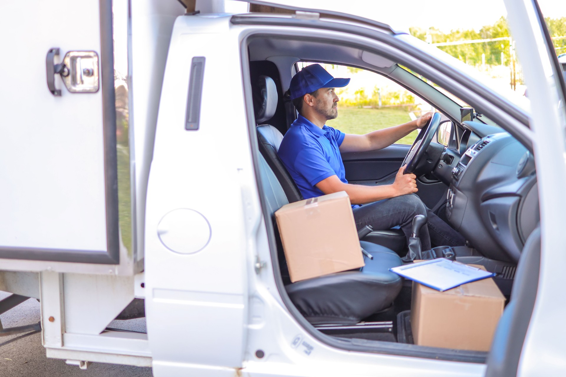 a courier in a white truck transports cardboard boxes around the city. concept food delivery, delivery services